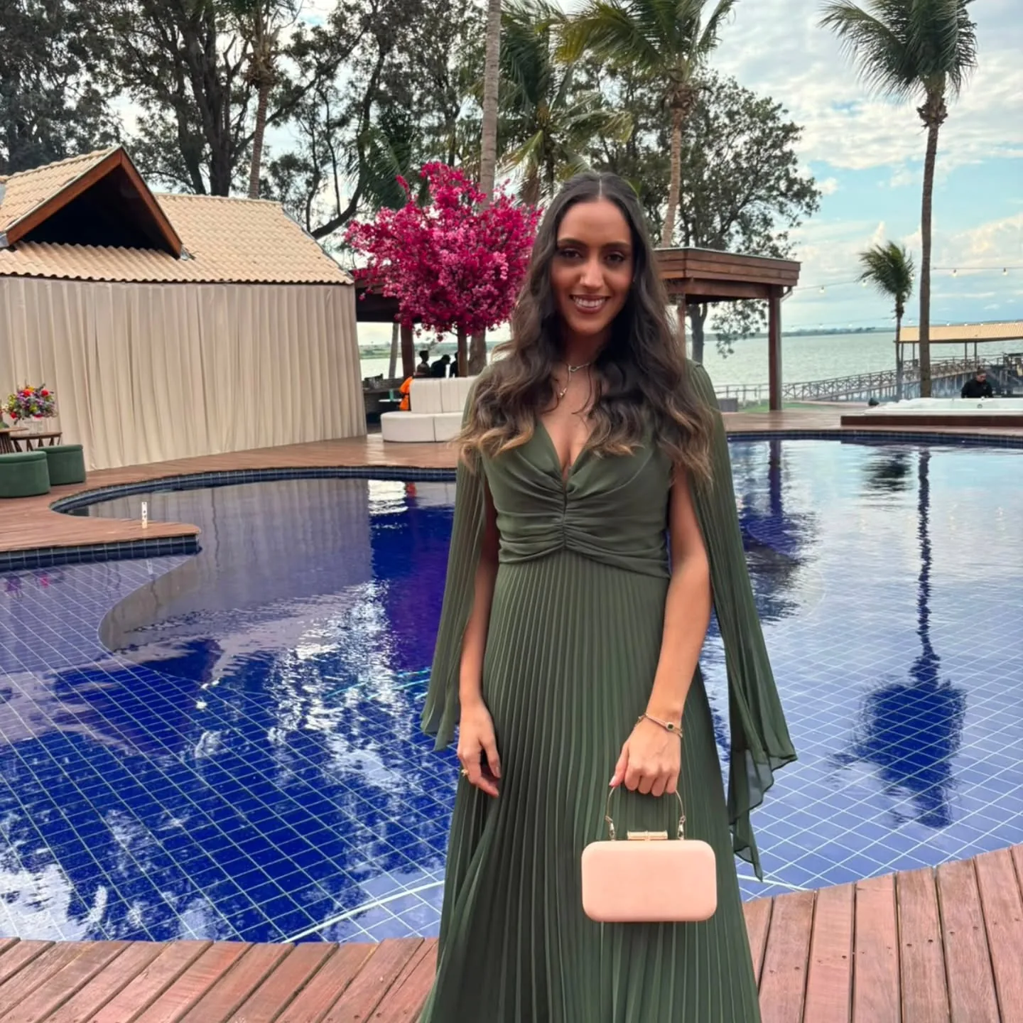 Thayane de vestido verde ao pôr do sol, sorrindo, em outra pose da mesma sessão
