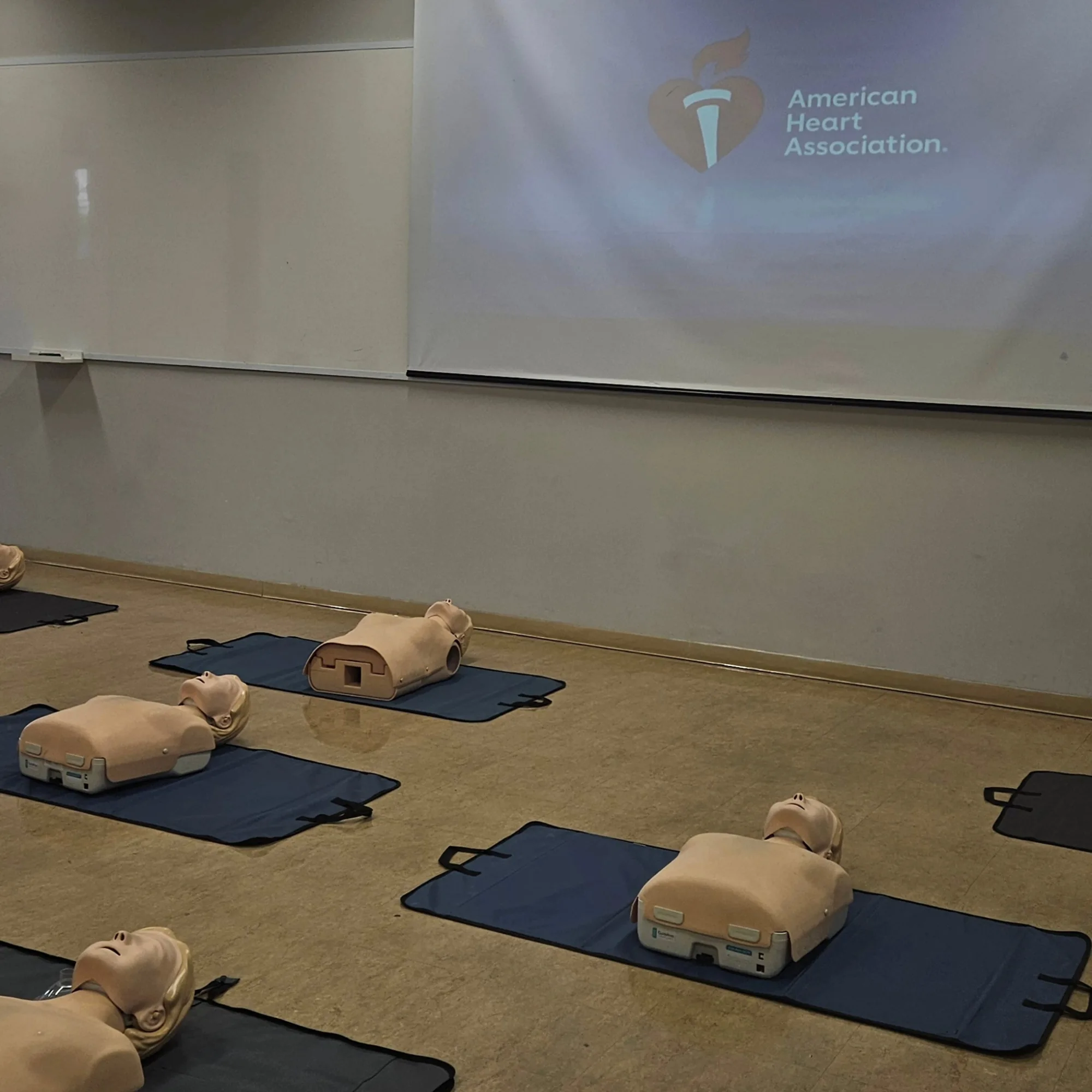 Sala de treinamento com manequins de RCP sobre tapetes